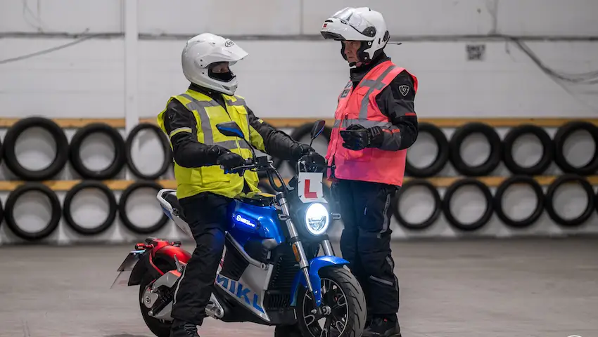 Instructor in hi-vis coaching a student on a training bike