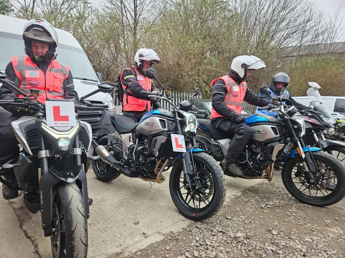 CBT students in hi-vis vests on 125cc motorcycles with L-plates at the Edinburgh Motorcycle Training yard in Straiton