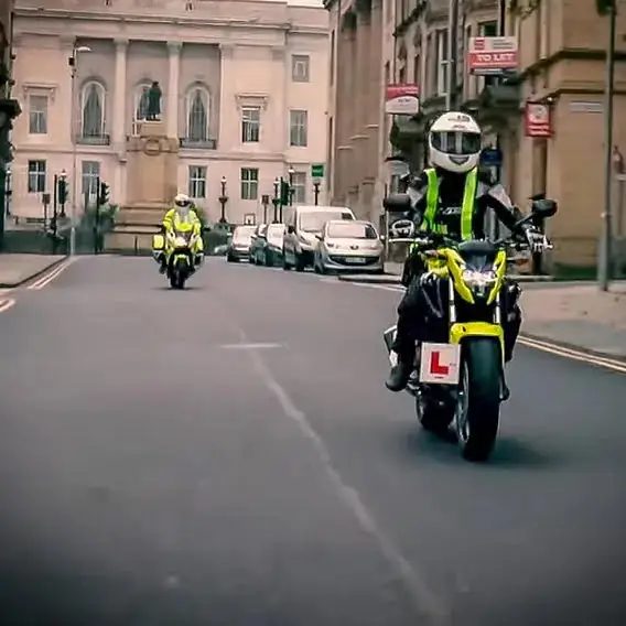 Learner rider with L-plates on a guided road ride followed by an instructor